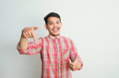 Asyalı bir adam gülümser ve eliyle bir şeye işaret eder, reklam kavramları.