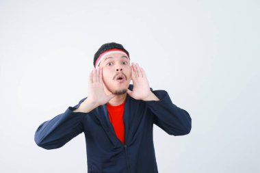 Heyecanlı genç Asyalı adam bağırıyor ve bağırıyor, elleri ağzında. Endonezya 'nın bağımsızlık günü konsepti.