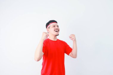 Excited young Asian man clenched fist showing excitement during celebrating indonesian independence day on 17 august isolated on white background