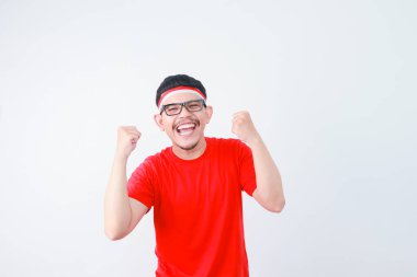 Excited young Asian man clenched fist showing excitement during celebrating indonesian independence day on 17 august isolated on white background