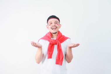 Heyecanlı genç Asyalı adam, Endonezya 'nın bağımsızlık gününü beyaz arka planda 17 Ağustos' ta kutlarken kollarını açıp heyecanını gösteriyor.