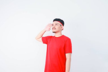 Genç Asyalı adam, beyaz arka planda izole edilmiş özgüvenle selam veriyor ve saygılı jestler yapıyor. Endonezya 'nın bağımsızlık gününü 17 Ağustos' ta kutlayın