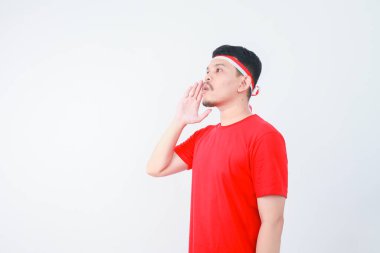 Heyecanlı genç Asyalı adam bağırıyor ve bağırıyor, elleri ağzında. Endonezya 'nın bağımsızlık günü konsepti.