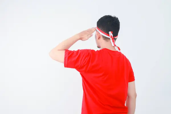 stock image Back view young Asian man standing confidently giving a salute and respectful gestures isolated over white background. Celebrate Indonesia independence day on 17 August