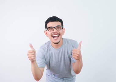 Asyalı genç adam gülümsüyor ve baş parmak işareti yapıyor.