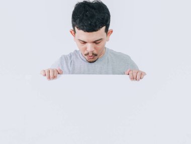 Asyalı adamın pankartı boş tutarken ya da slogan için telif alanı tutarken aşağıya bakmasının şok edici ifadesi