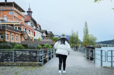 Kış kıyafetleri giyen Asyalı bir kadın, Brienz İsviçre 'nin manzarasının tadını çıkarıyor.
