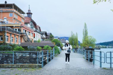 Kış kıyafetleri giyen Asyalı bir kadın, Brienz İsviçre 'nin manzarasının tadını çıkarıyor.