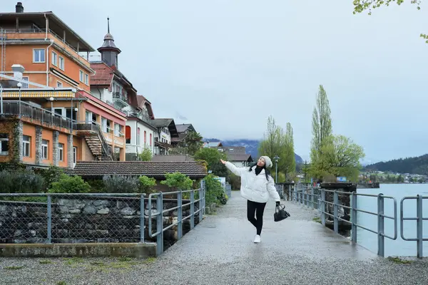 Kış kıyafetleri giyen Asyalı bir kadın, Brienz İsviçre 'nin manzarasının tadını çıkarıyor.