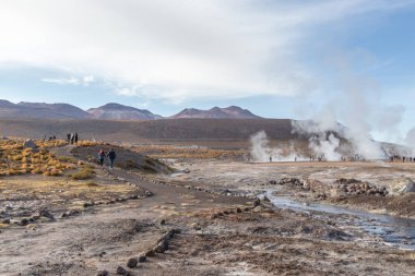 Şili 'nin Bolivya sınırındaki Atacama Çölü' nün volkanik bölgesinde El Tatio Gayzerlerinin dumanıyla çevrili insanlar.