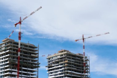 Konut binalarının inşaatı. Arka planda mavi gökyüzü olan bitkileri inşa etmek için vinçler.