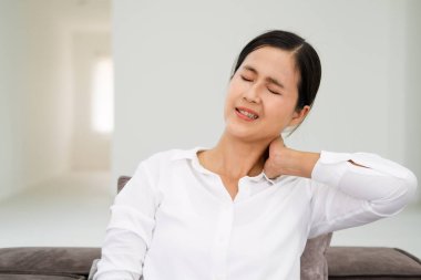 Sağlıksız koyu renk saçlı kadın boynuna dokunuyor ağrı ve uyuşukluk hissediyor kas gerilimi, osteokondrosis, günlük tarz gömlek giyiyor. Beyaz arka planda izole edilmiş bir oturma odası..