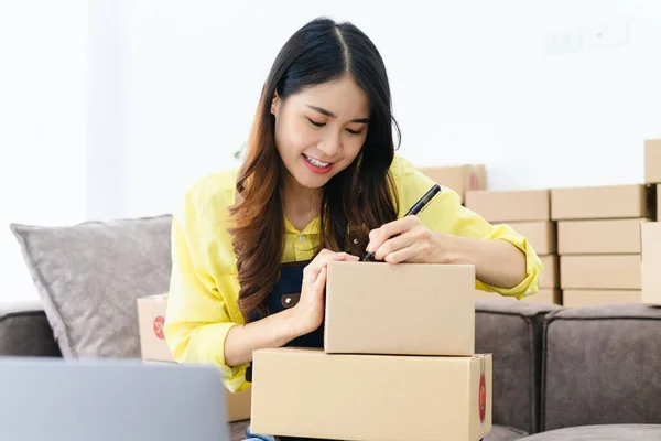 stock image Young entrepreneur, teenager business owner work at home, alpha generation life style. Business woman online seller write down address on parcel box for deliver