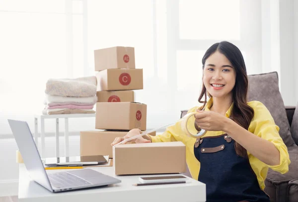 Ev ofisindeki karton kutuda küçük bir işletme sahibi var. Çevrimiçi satış bürosunda teslimat için paket hazırlayan bir kadın. Girişimciler Paket Kutuları Başlangıç Fikirleri ile Mal Düzenleme.