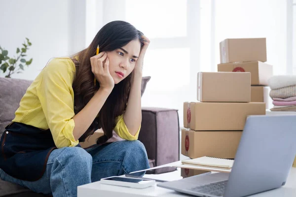 stock image Asian woman think hard serious working laptop computer at home selling online start up small business owner, e-commerce ideas concept.