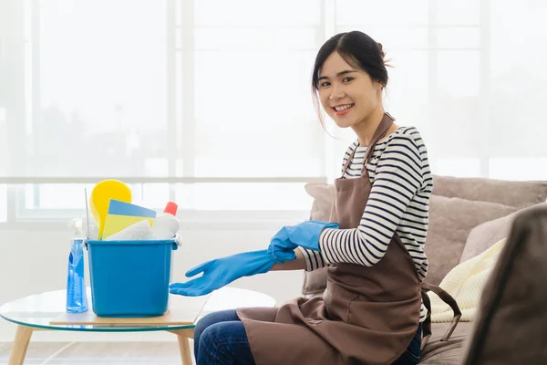 笑着穿围裙的年轻亚洲女人戴上橡胶手套 准备在客厅里做家务活 家庭主妇有乐趣和许多家务活 家务活和专业清洁服务 — 图库照片