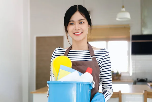 千禧年女佣拿着装有清洁用品的桶在室内 手牵手 用洗涤剂裁剪家庭主妇的照片 准备好了打扫房子 卫生服务概念 — 图库照片