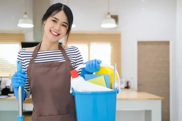千禧年女佣拿着装有清洁用品的桶在室内 手牵手 用洗涤剂裁剪家庭主妇的照片 准备好了打扫房子 卫生服务概念 — 图库照片