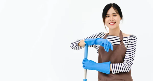 快乐的年轻女性 戴着蓝色橡胶手套进行护手 拿着拖把 对着相机微笑 同时在白色背景下清扫房子 — 图库照片