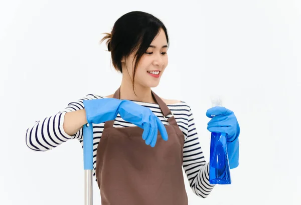 快乐的年轻女子戴着蓝色橡胶手套进行护手 拿着拖把和喷雾器 一边对着相机微笑 一边在白色背景下清扫房子 — 图库照片