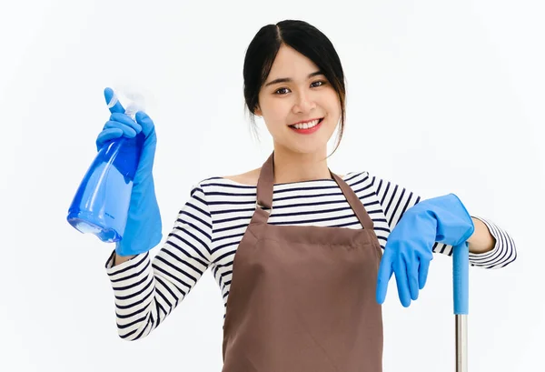 快乐的年轻女子戴着蓝色橡胶手套进行护手 拿着拖把和喷雾器 一边对着相机微笑 一边在白色背景下清扫房子 — 图库照片
