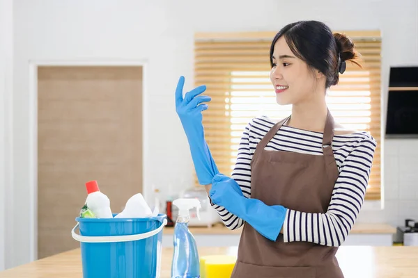 Uśmiechnięta Młoda Azjatka Fartuchu Zakłada Gumowe Rękawiczki Gotowa Prac Domowych — Zdjęcie stockowe