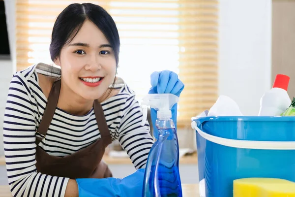 消毒和清洁的概念 那位穿着围裙和橡胶手套的女士 手里拿着装有一桶清洁用品的喷雾瓶在厨房里 — 图库照片