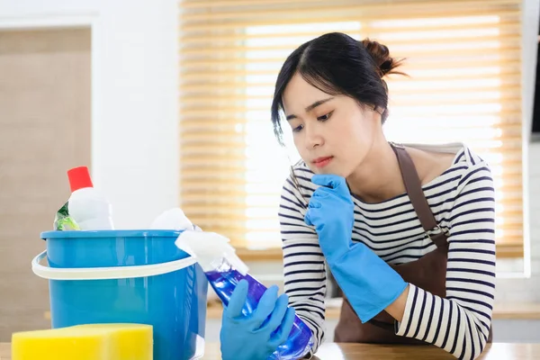 厨房里穿着棕色围裙和蓝色橡胶手套 戴着清洁用品喷雾瓶的女人的衣服 在家里读说明书 有毒清洁用品概念 — 图库照片