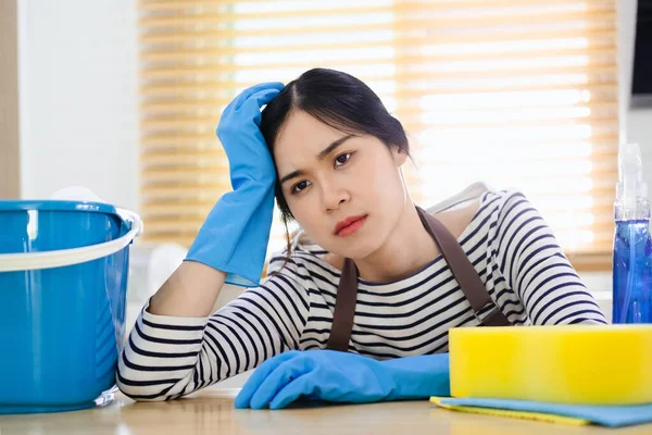 疲惫的年轻妇女 带着清洁用品和设备坐在厨房里 家务活概念 — 图库照片