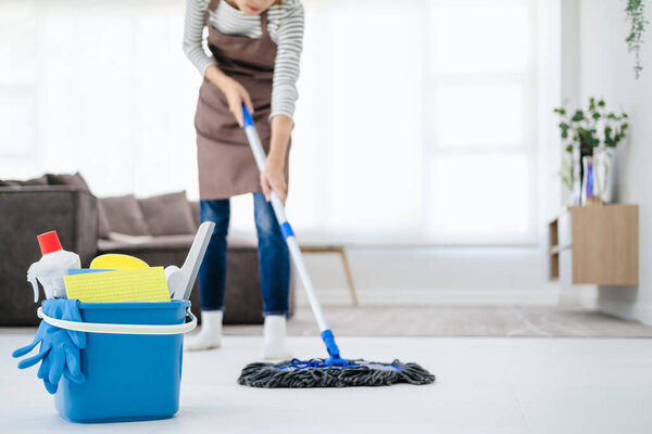 Cropped image of beautiful young woman in protective gloves using a flat wet-mop while cleaning floor in the house