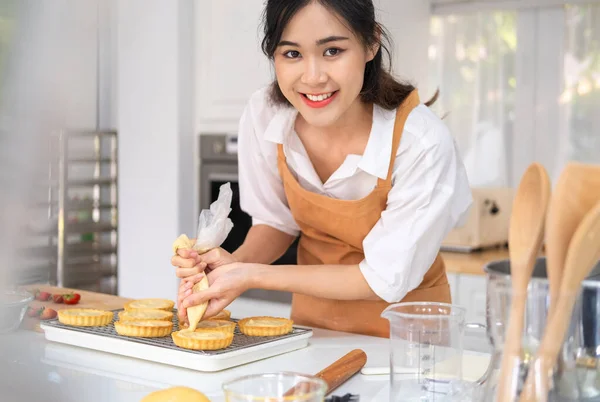 小商业企业家亚洲女人面包店制作水果馅饼 女性贝克在白色厨房柜台上用软糖袋装饰水果馅饼 室内生活方式概念 — 图库照片