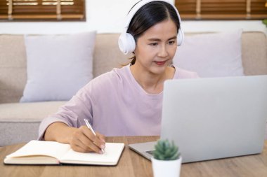 Çekici kız öğrenci öğrenme dili, çevrimiçi webinar izleme, sesli kurs dinleme, kulaklık takan kadın kafede dizüstü bilgisayar kullanma, notlar yazma, e-öğrenim konsepti