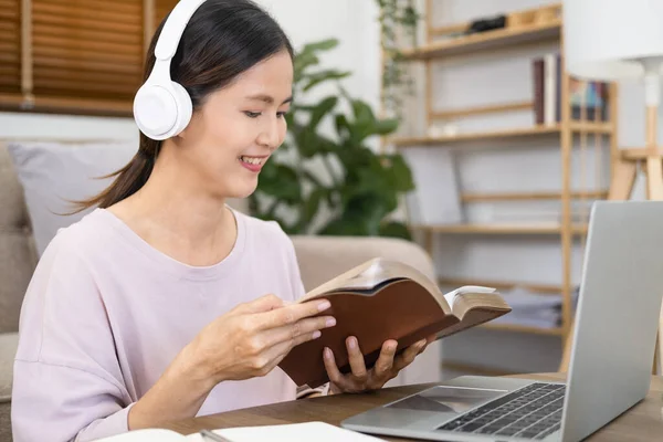 Young female student study in home.She using laptop and learning online. Attractive female student  watching online webinar,woman wearing headphones listening audio course , e-learning education.