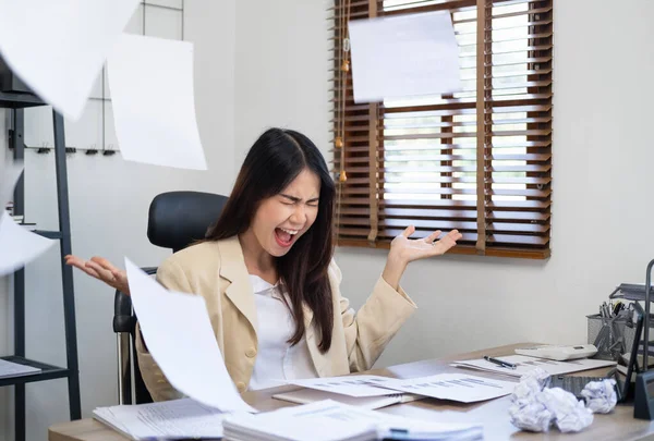 Businesswoman sitting with head in hands at desk covered crumpled papers. Office worker tired of too much difficult unproductive work. Stressed female entrepreneur has no idea what to do with problem