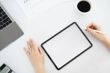 İş kadınının iş yerinde doküman ve tabletle uğraşırken yüksek açılı görünümü.