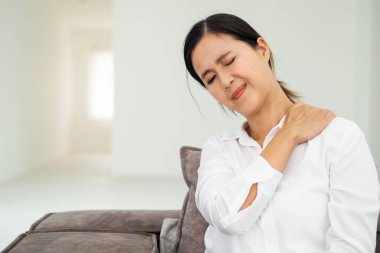 Sağlıksız koyu renk saçlı kadın boynuna dokunuyor ağrı ve uyuşukluk hissediyor kas gerilimi, osteokondrosis, günlük tarz gömlek giyiyor. Beyaz arka planda izole edilmiş bir oturma odası..