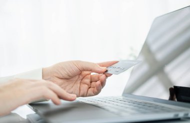 Kredi kartı tutan ve dizüstü bilgisayar kullanan eller. İnternetten alışveriş