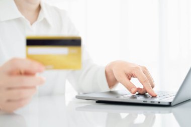 Kadının elinde kredi kartı, evinde dizüstü bilgisayar, online alışveriş ve fatura ödeme metodu var..