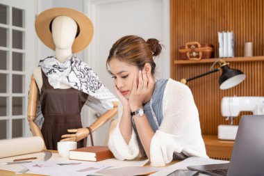 Moda tasarımı hakkında düşünen genç bir kadın. Konsantre kadın moda tasarımcısı kağıt düşünüyor, yaratıcı iş yerinde çalışıyor..