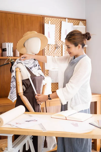 A few finishing touches and itll be ready. Shot of a young fashion designer working on a garment hanging over a mannequin.