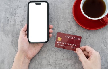 İnternet konseptinde online alışveriş. Modern cilalanmış beton ofis masasında kredi kartı ve boş akıllı telefon kullanan bir kadın..