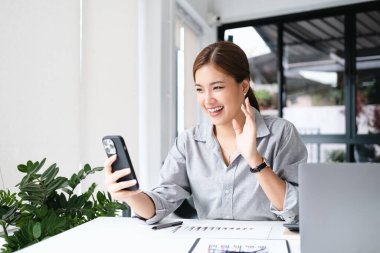 Görüntülü arama. Neşeli genç iş kadını cep telefonuyla arkadaşlarıyla konuşuyor.,