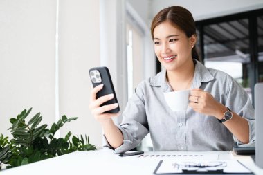 Görüntülü arama. Neşeli genç iş kadını cep telefonuyla arkadaşlarıyla konuşuyor., 