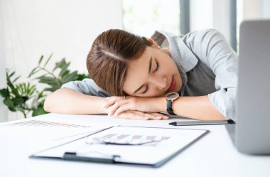 Çok çalışan ve yorgun bir işkadını masa başında çalışma ofisinde bir dizüstü bilgisayar üzerinde uyku