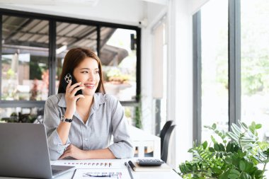 Genç kadın Office konuşurken birileriyle onun cep telefonu süre seyir içine mesafe mutlu yüz ifadesi ile kapatmak.