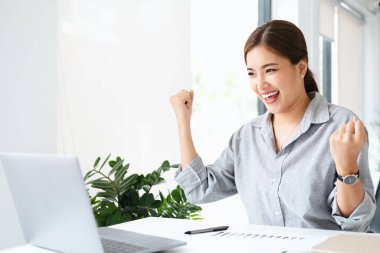 Asyalı kız bunu cep telefonu ve dizüstü bilgisayarla kutluyor, başarı pozu veriyor. E-ticaret, üniversite eğitimi, internet teknolojisi ya da küçük işletme konsepti. Kopyalama alanı olan modern ofis