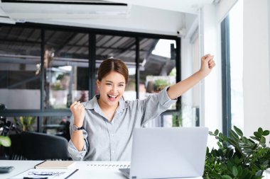 Ofis bilgisayarında çalışan gülümseyen Asyalı güzel bir iş kadını. Küçük işletmeler çalışanlarının serbest çalışanları Asyalı tasarımcıları pazarlamaya başladı.