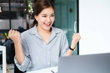 Ofis bilgisayarında çalışan gülümseyen Asyalı güzel bir iş kadını. Küçük işletmeler çalışanlarının serbest çalışanları Asyalı tasarımcıları pazarlamaya başladı.