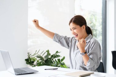Ofis bilgisayarında çalışan gülümseyen Asyalı güzel bir iş kadını. Küçük işletmeler çalışanlarının serbest çalışanları Asyalı tasarımcıları pazarlamaya başladı.