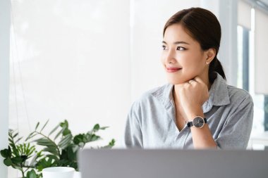 İşi teknolojik seviyeye nasıl çıkaracağımı düşünüyordum. Gülümseyen neşeli genç iş kadını modern ofiste çalışıyor..